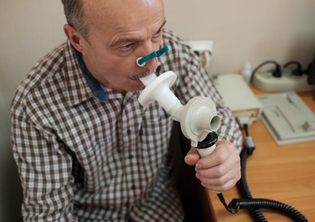Senior hispanic man man testing breathing function by spirometry
